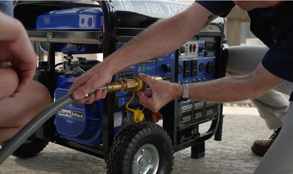 Two people connecting a hose to a portable DuroMax generator.