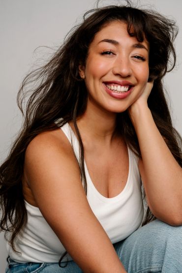 Smiling woman in a white tank top and jeans.
