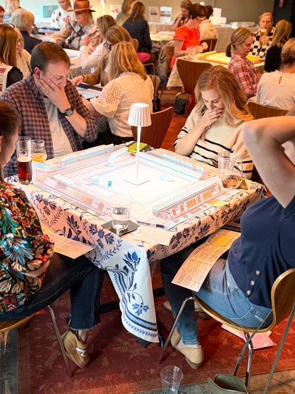large group of mahjong players in Charlotte at a mahjong event playing mahjong at several tables