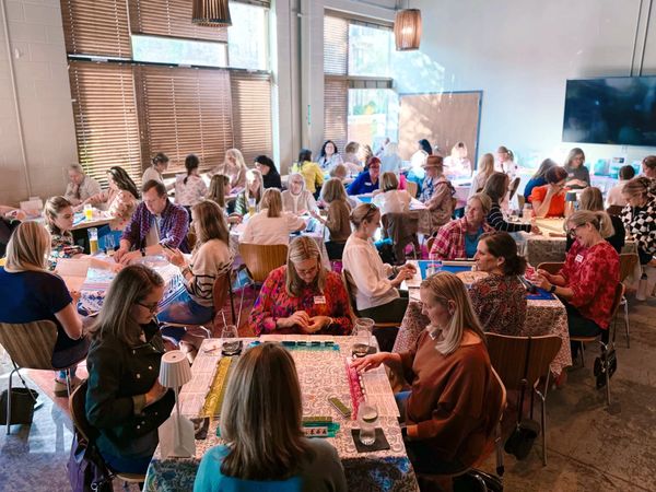 large group of mahjong players in Charlotte at a mahjong event playing mahjong at several tables
