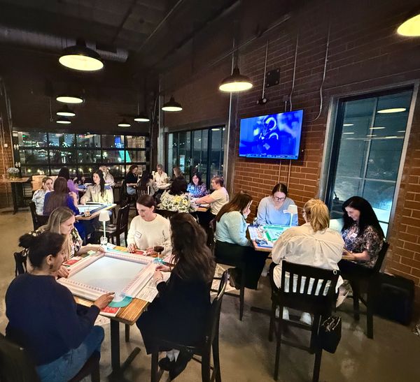 large group of mahjong players in Charlotte at a mahjong event playing mahjong at several tables