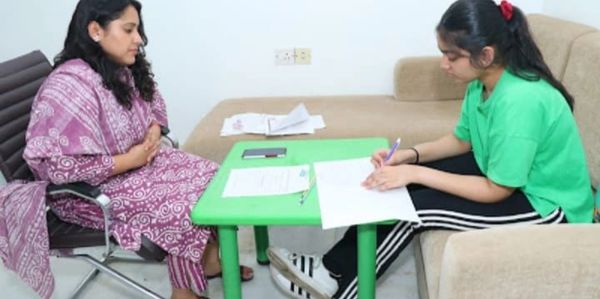 A woman and a girl engaged in paperwork at a table.