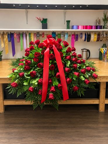 Large bouquet of red roses with a red ribbon on a wooden table.