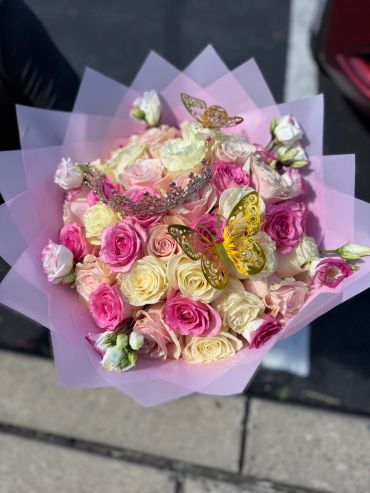 Bouquet of pink and cream roses with butterfly decorations.