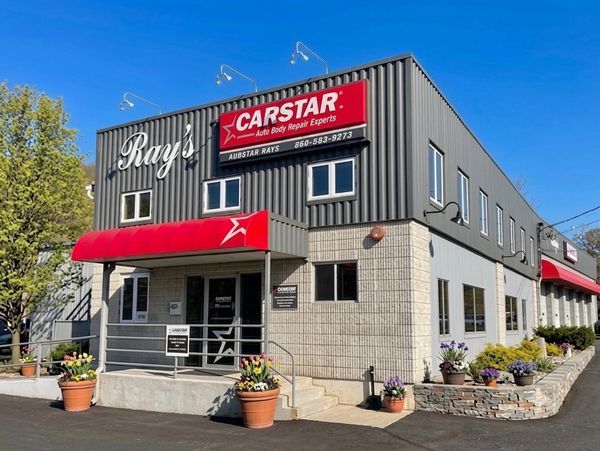 Exterior view of Ray's CARSTAR auto body repair shop under clear blue sky.