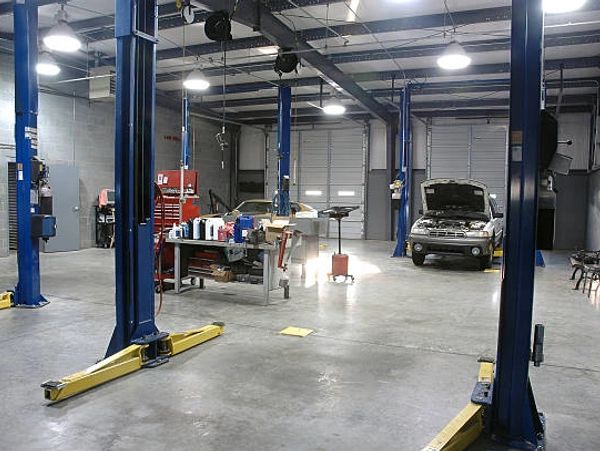 Spacious auto repair garage with tools and a car being serviced.