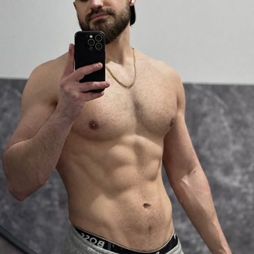 Man taking a shirtless mirror selfie showing toned abs and chest.