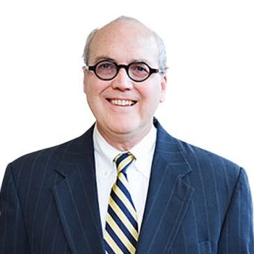 Smiling man in glasses wearing a suit and striped tie.