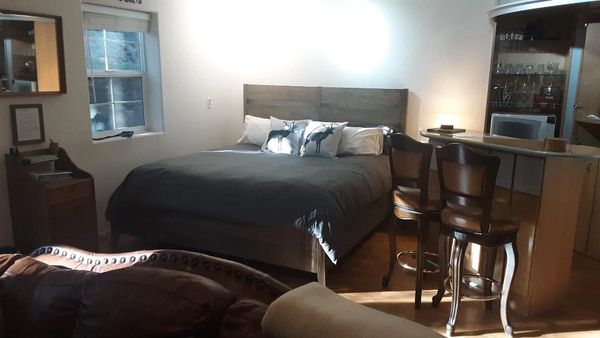 Cozy bedroom with a large bed, pillows, and a small bar area with stools.