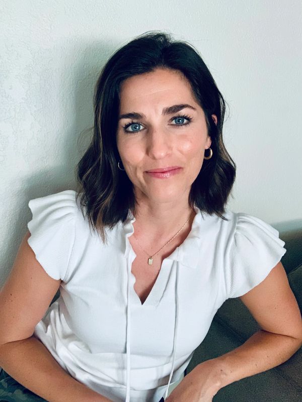Woman with blue eyes and dark shoulder-length hair wearing a white top.