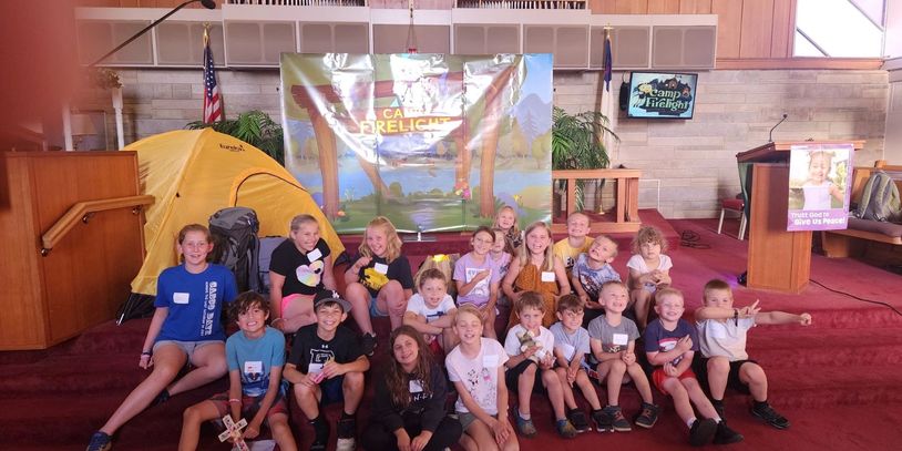 Group of children at Camp Firelight posing indoors with a yellow tent.