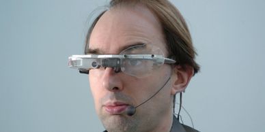 Man wearing futuristic augmented reality glasses with a microphone headset.