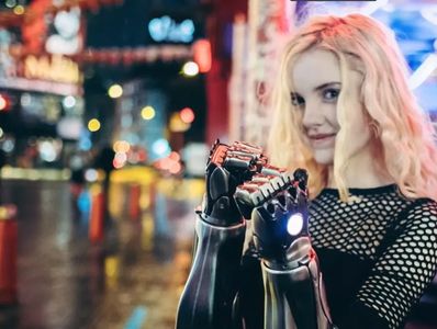 A woman with robotic hands poses in a vibrant city at night.
