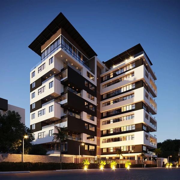 Modern black and white apartment building illuminated at dusk.