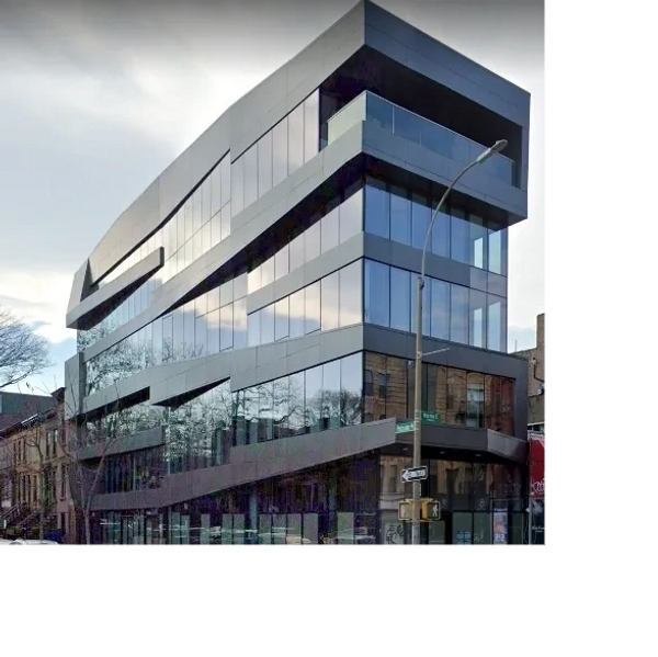 Modern glass building with angular design on a city street corner.