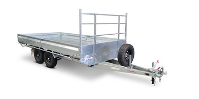 A galvanized flatbed trailer with dual wheels and a spare tire mounted on the front.