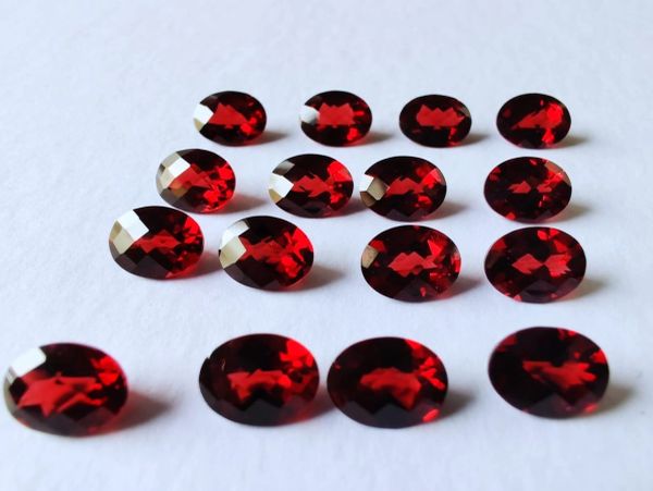 Rows of red oval-shaped gemstones on white background.