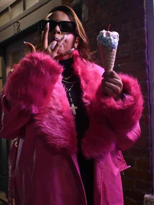 Person in a pink fur coat holding an ice cream cone.