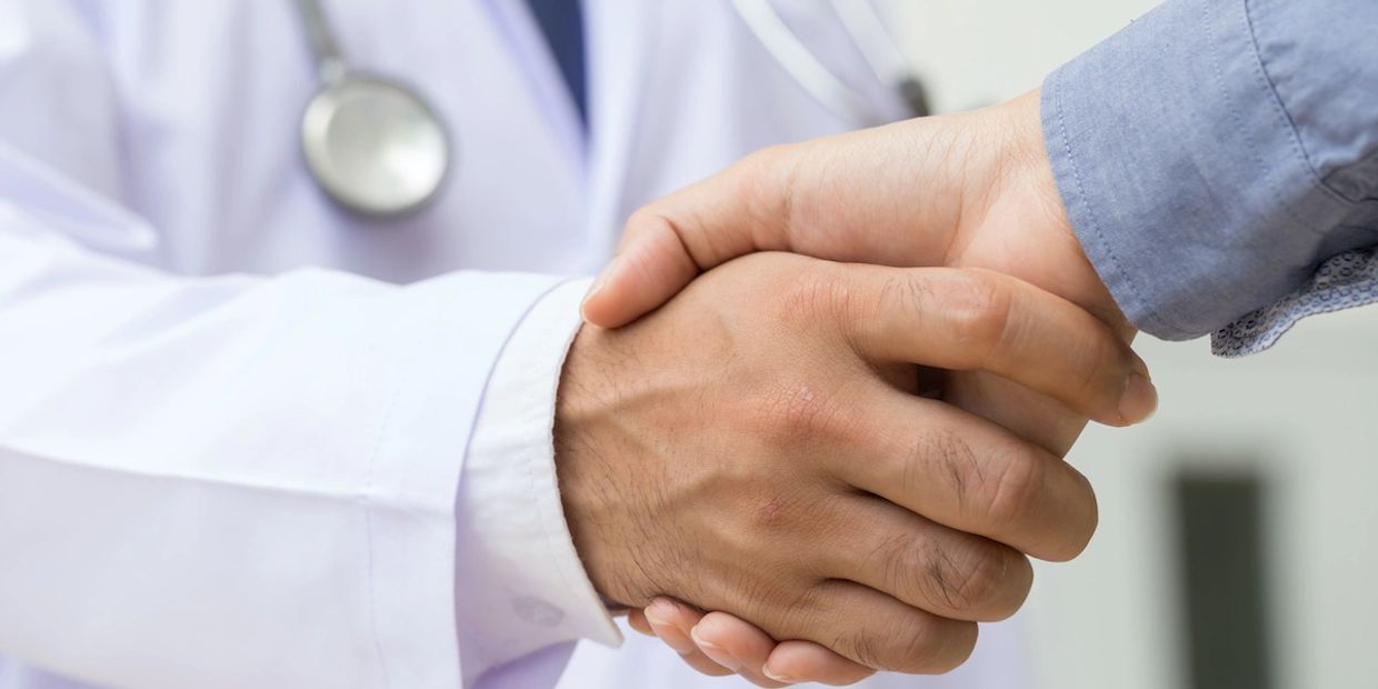 Doctor and patient shaking hands in a medical setting.