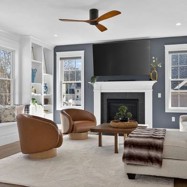 Modern living room with brown chairs, a fireplace, and a ceiling fan.