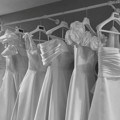 Collection of white dresses on hangers.