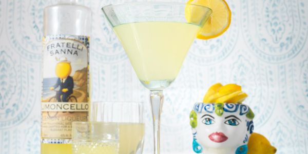 A refreshing lemon cocktail with limoncello and decorative lemon-themed items.