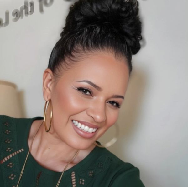 Smiling woman with a stylish bun and gold hoop earrings.