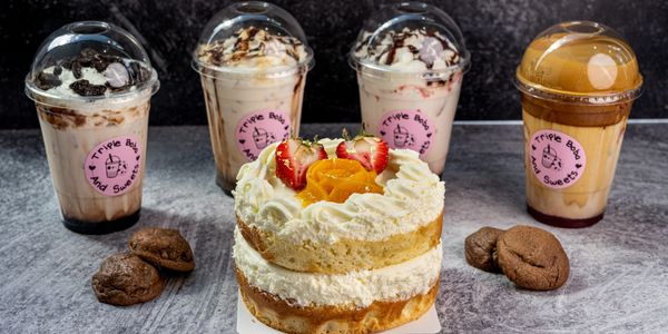 Dessert spread with a layered cake, cookies, and boba tea drinks.
