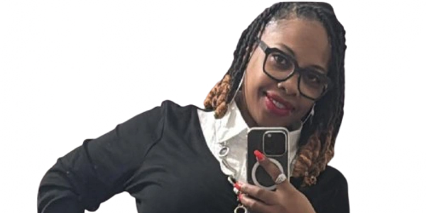 Woman taking a mirror selfie, smiling with glasses and a casual outfit.