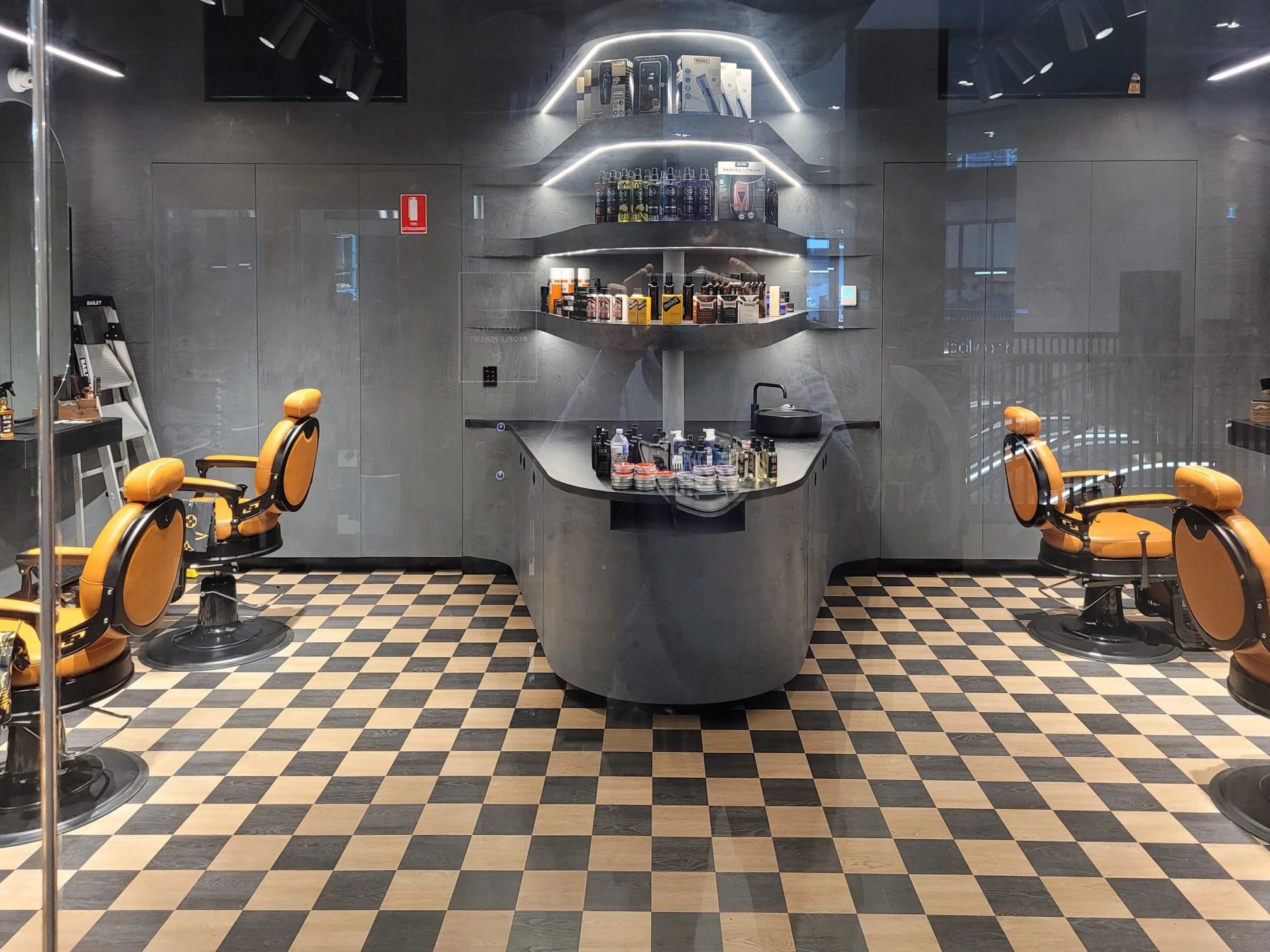 Modern barbershop interior with orange chairs and checkered floor.