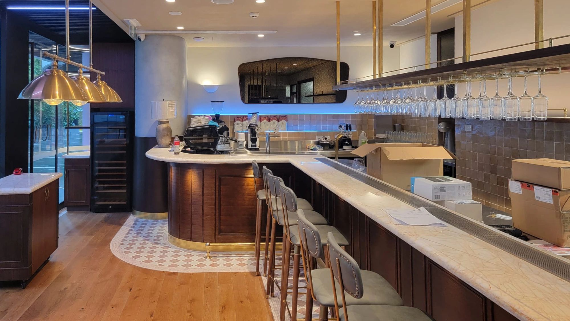 Modern bar with marble counter and hanging glasses.