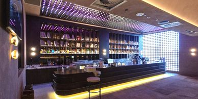 Modern bar with illuminated shelves and seating.