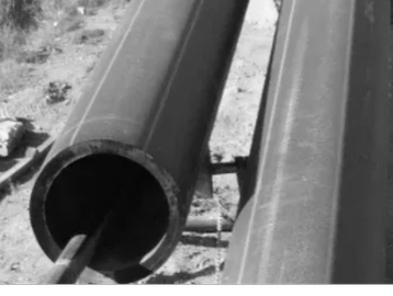 Two large industrial pipes lying on the ground outdoors.