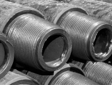 Close-up of threaded metal pipes stacked together.