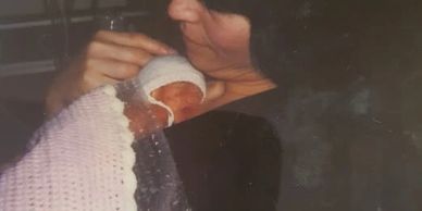 A woman tenderly holds a premature baby wrapped in a blanket.