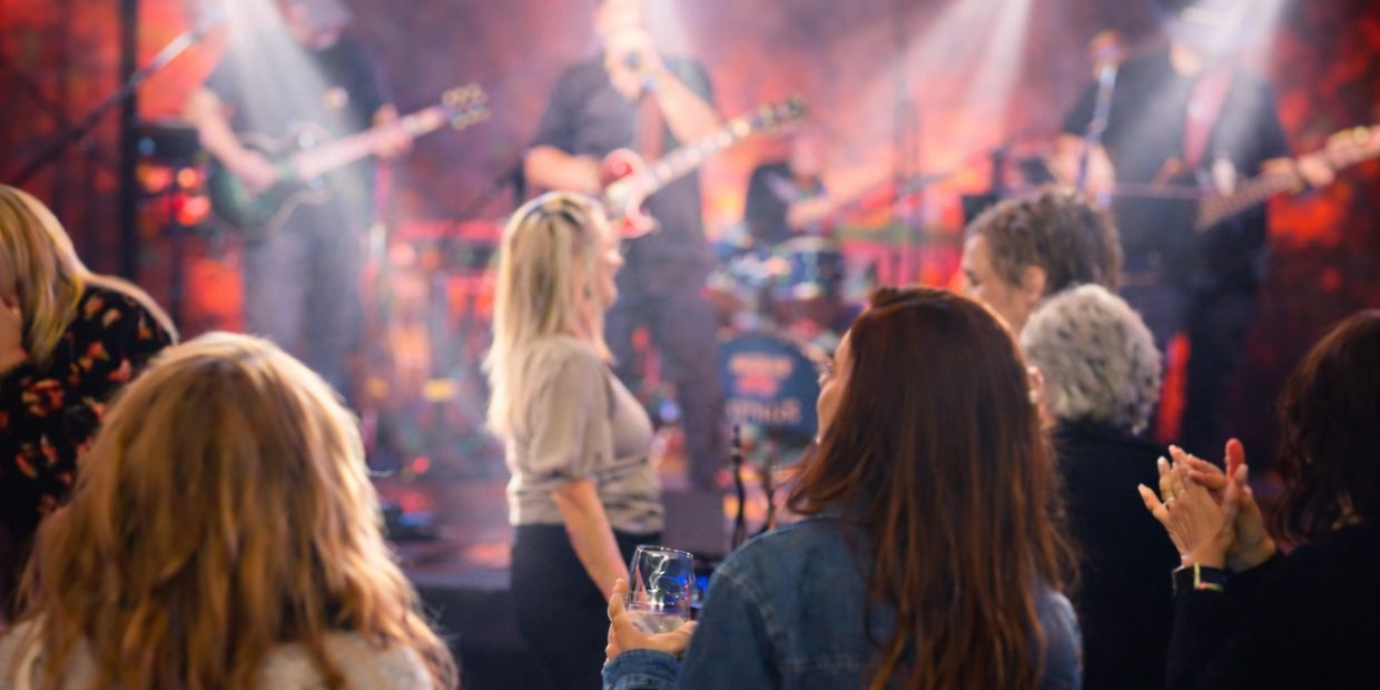 People enjoying a live band performance with drinks and applause.