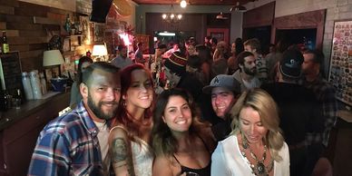 A group of friends smiling and posing in a lively bar setting.