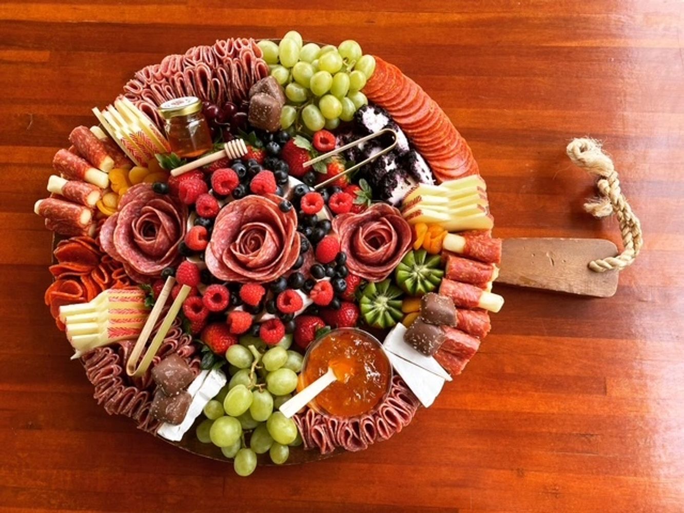 Elegant charcuterie board with meats, cheeses, fruits, and preserves arranged beautifully.