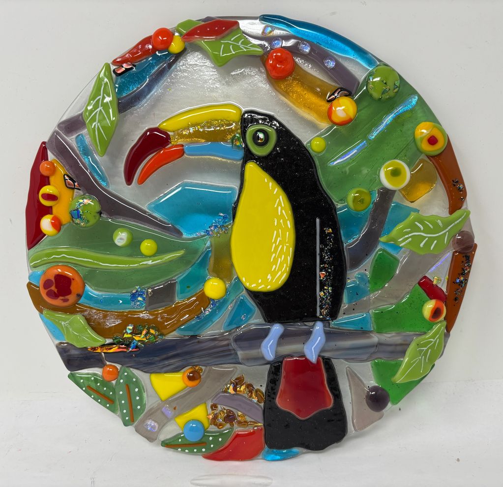 Colorful glass artwork of a toucan on a branch.
