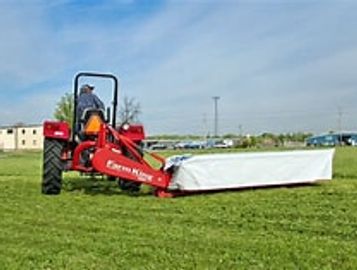 A person operating a red Exmark mower on a grassy field.