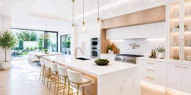 Modern white kitchen with large island and gold-accented stools.