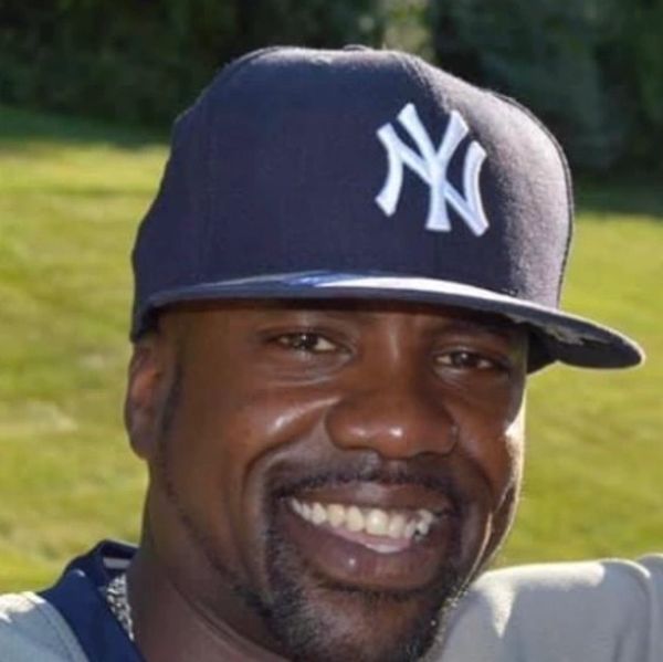 Man smiling wearing a New York Yankees cap.