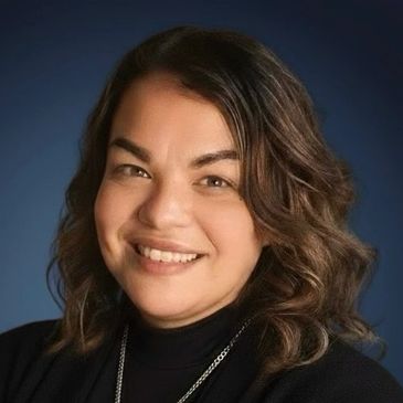 Smiling woman with wavy hair against a dark blue background.