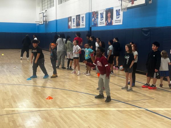 Children lined up in a gym for a basketball activity.