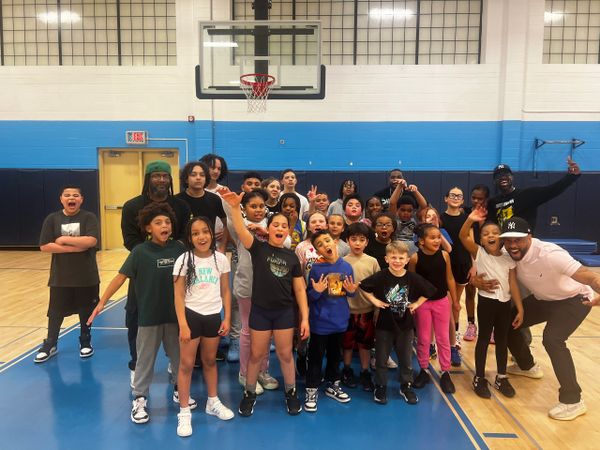 A diverse group of children and adults happily posing in a gymnasium.