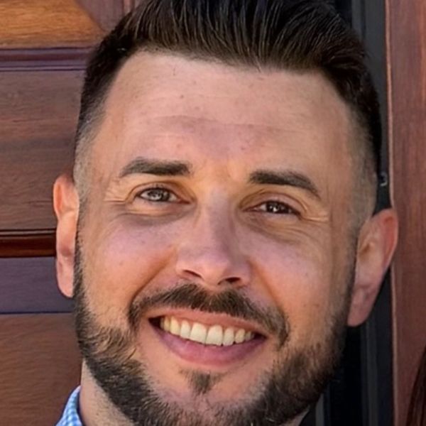 Smiling man with neatly trimmed beard and short hair.