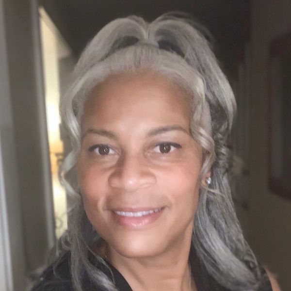 Smiling woman with gray hair styled in a high ponytail.