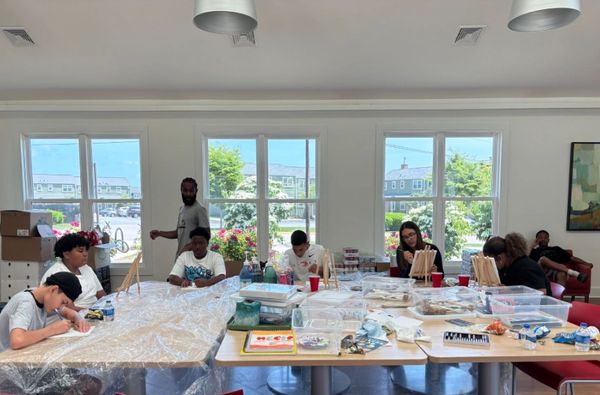 A group painting and drawing in a bright art room with large windows.