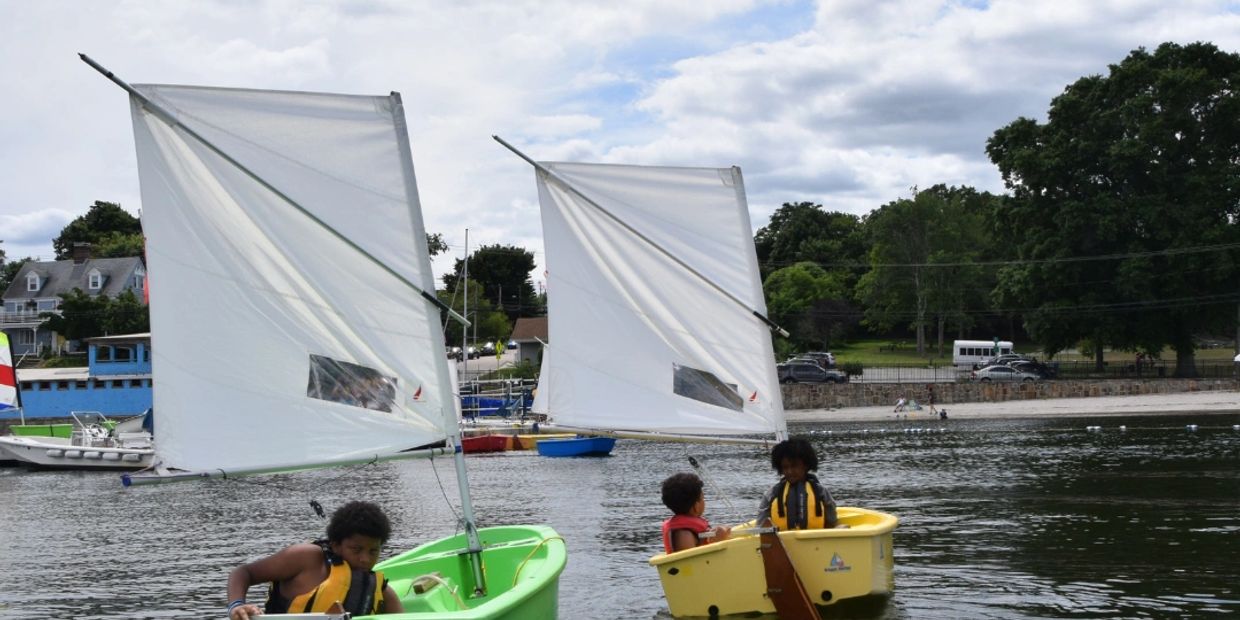 Children sailing small boats on a calm lake near the shore.