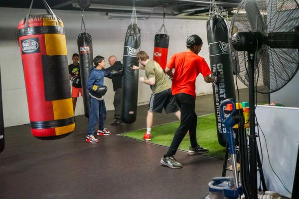 People training with punching bags in a boxing gym.